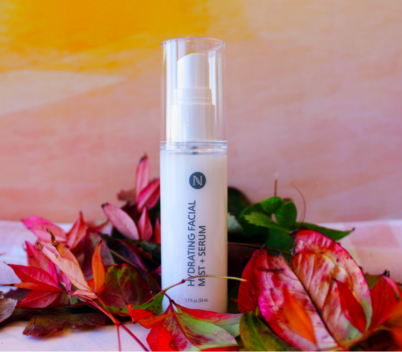 Neora's Hydrating Facial Mist sitting in a bed of autumn flowers.